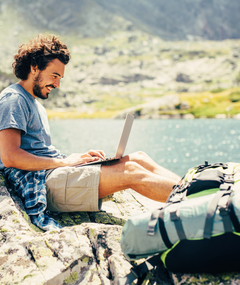 Man working on his laptop next to lake